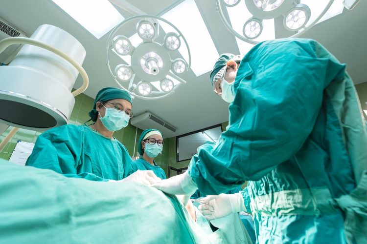 Zespół chirurgów podczas operacji na sali zabiegowej pod lampami operacyjnymi.